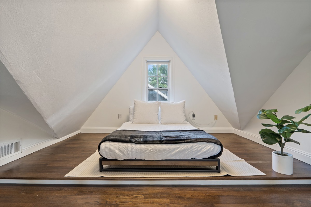 Open loft Double Bed with vaulted ceiling, natural light, and hotel-style linens. Extra pillows and blankets provided. Upper level of main house, open layout with room-darkening shades and clothing storage.