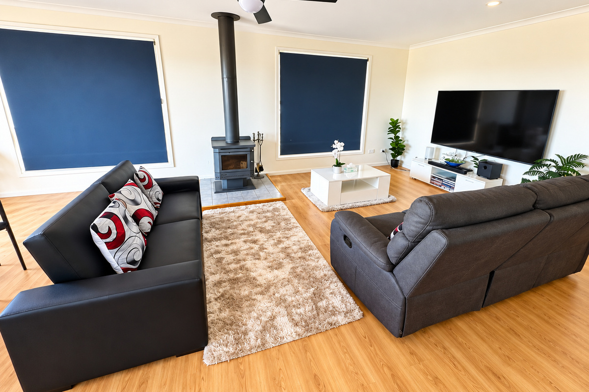 A comfortable spot to gather at Carlenes Getaway, featuring generous sofa seating, a cosy fireplace, large TV and warm timber floors.