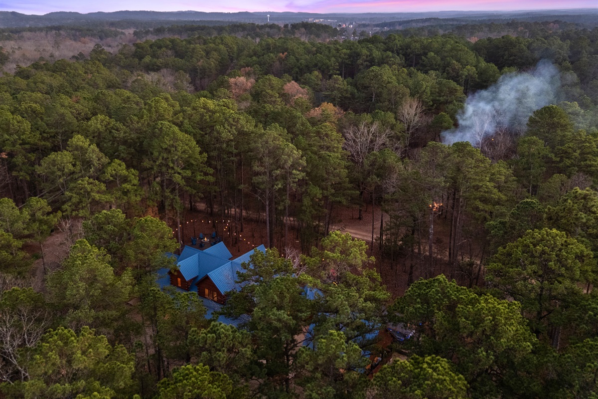 An aerial perspective shows the dense forest surrounding the property, adding to the sense of privacy and seclusion.