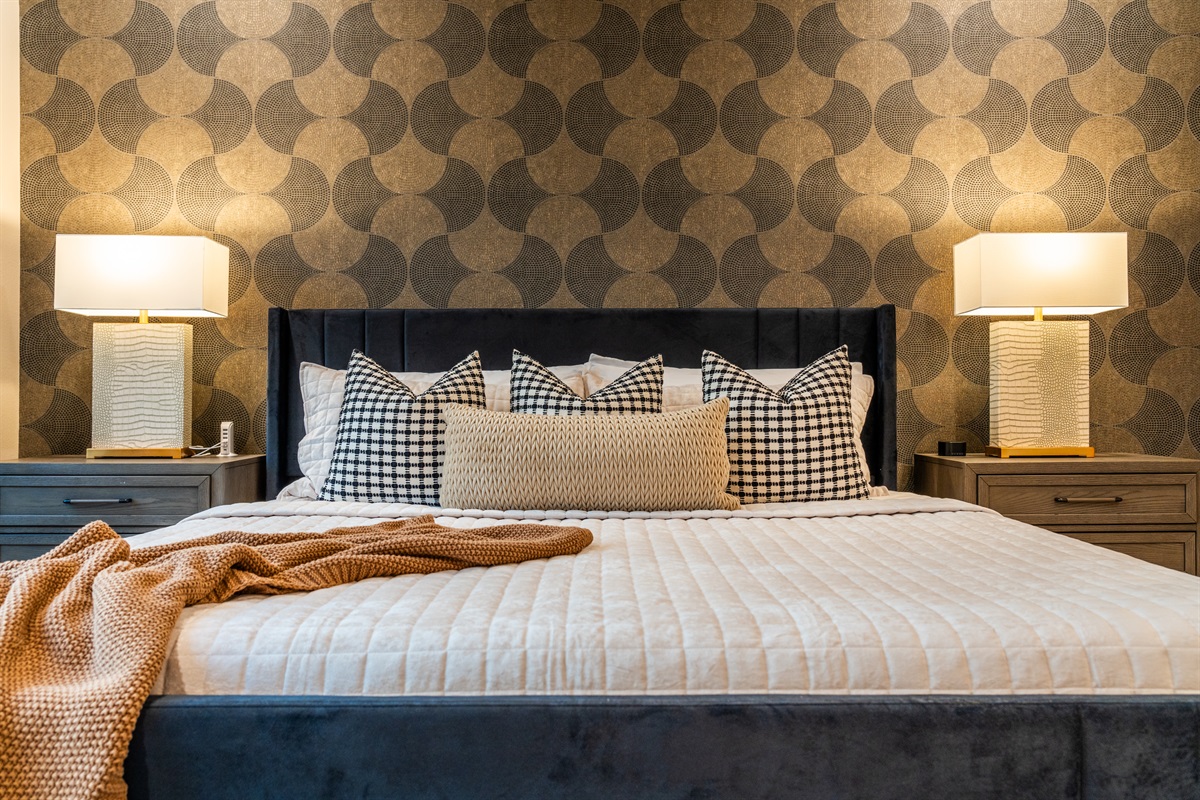 Detail-driven design shines here with textured linens and crafted pillows set against the backdrop of the patterned wall