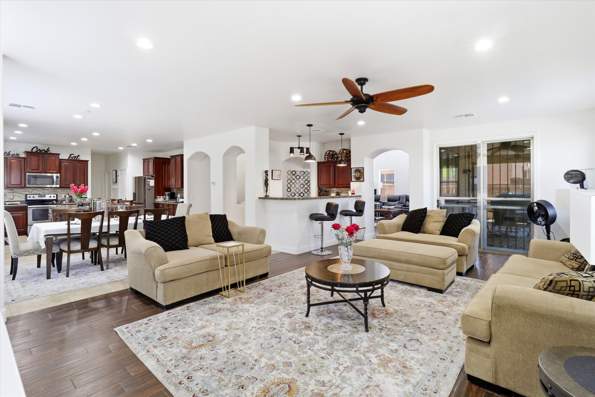 Living room with plenty of seating, patio access, and the kitchen and dining area close by.

