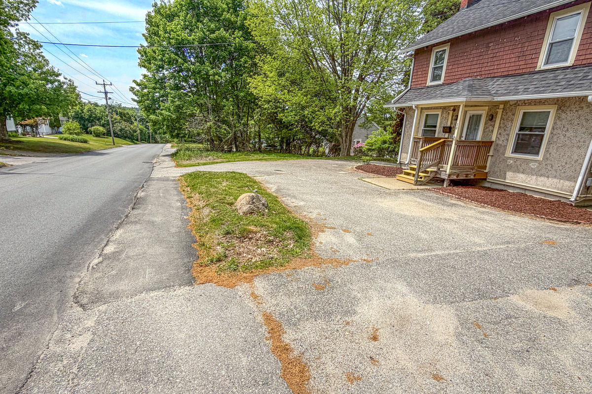 This detailed view of the private driveway entrance highlights the off-street vehicle parking area. Positioned for effortless street access, the paved footprint handles boat trailers and multiple passenger cars at this Downeast vacation home.