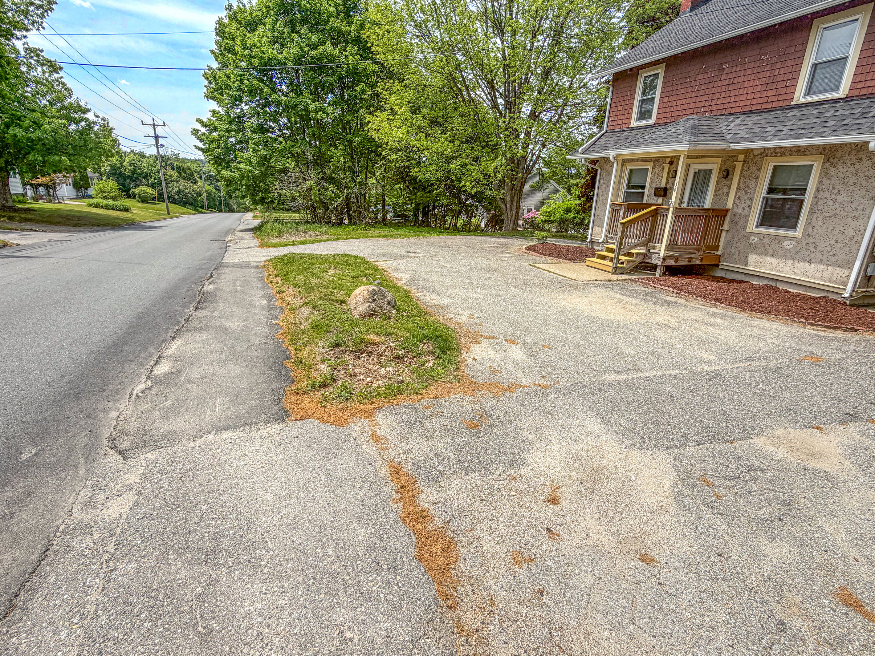 This detailed view of the private driveway entrance highlights the off-street vehicle parking area. Positioned for effortless street access, the paved footprint handles boat trailers and multiple passenger cars at this Downeast vacation home.