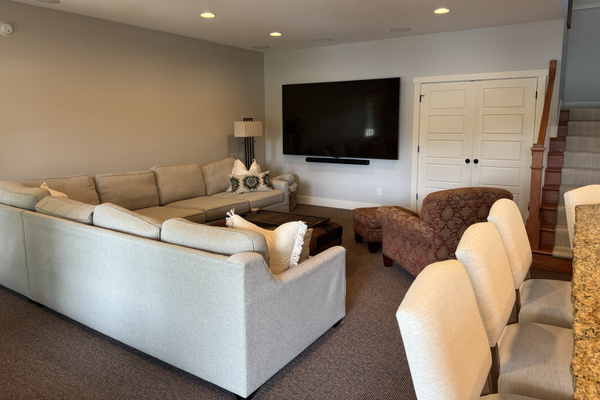 Expansive lower-level media room featuring a 100-inch TV, full bar, and lake views