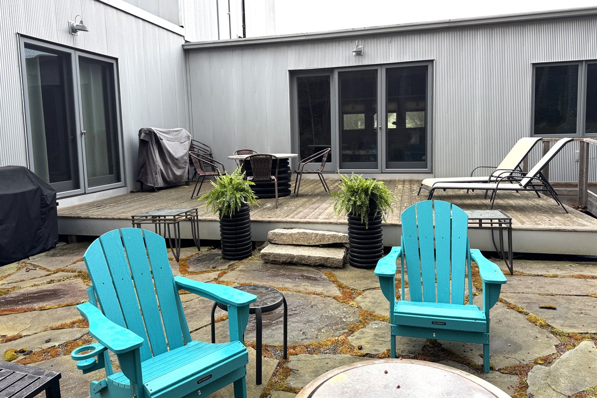 View from the natural granite yard and Solo Stove fire pit looking back at the 33ft deck. This outdoor oasis borders Acadia National Park, offering a seamless transition from the main level lounge to starlit nights by the fire.