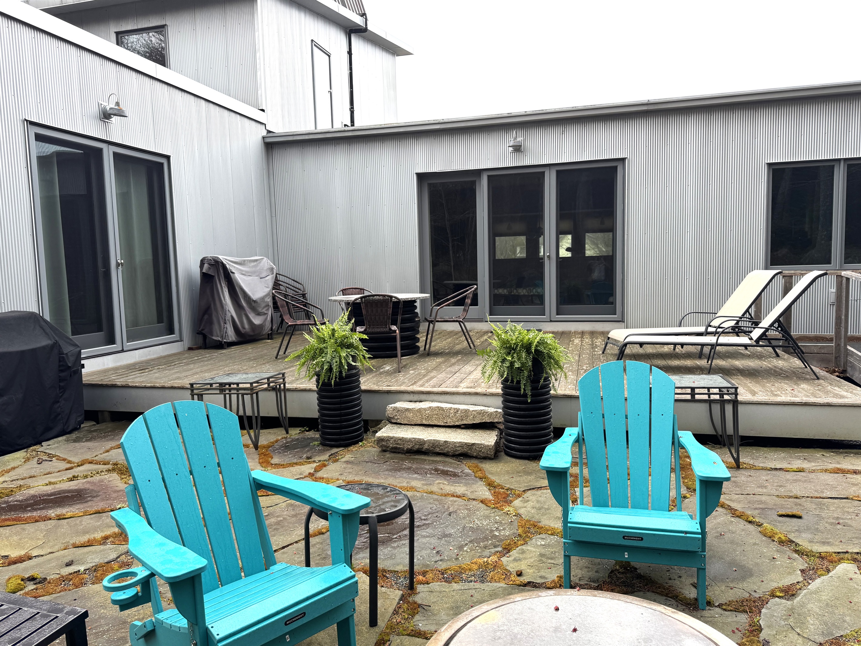 View from the natural granite yard and Solo Stove fire pit looking back at the 33ft deck. This outdoor oasis borders Acadia National Park, offering a seamless transition from the main level lounge to starlit nights by the fire.