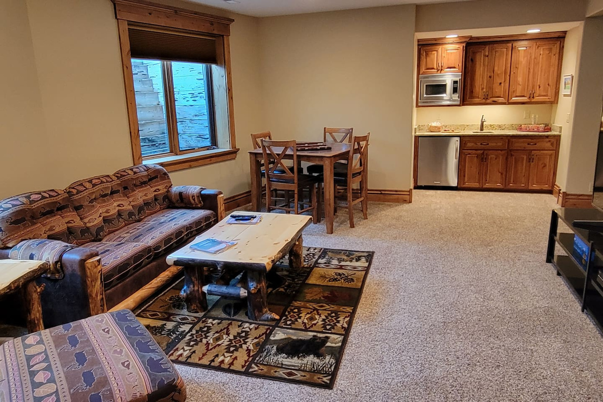 This inviting lower-level space serves as a perfect second living area, offering comfortable seating, a dining table, and a convenient kitchenette. Ideal for relaxing, movie nights, games, or creating additional gathering space! 