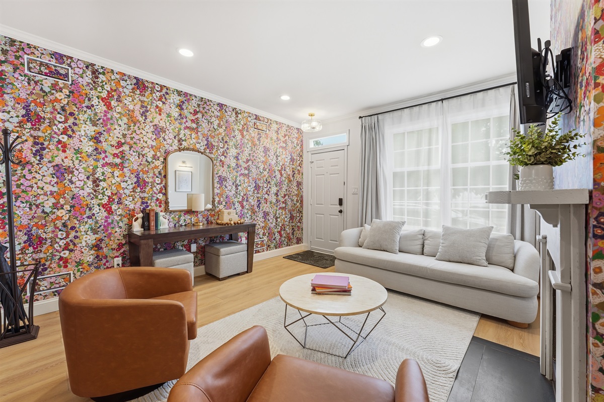 Bright and welcoming lounge space with statement floral wallpaper, oversized windows, plush seating, and boutique-inspired design details throughout