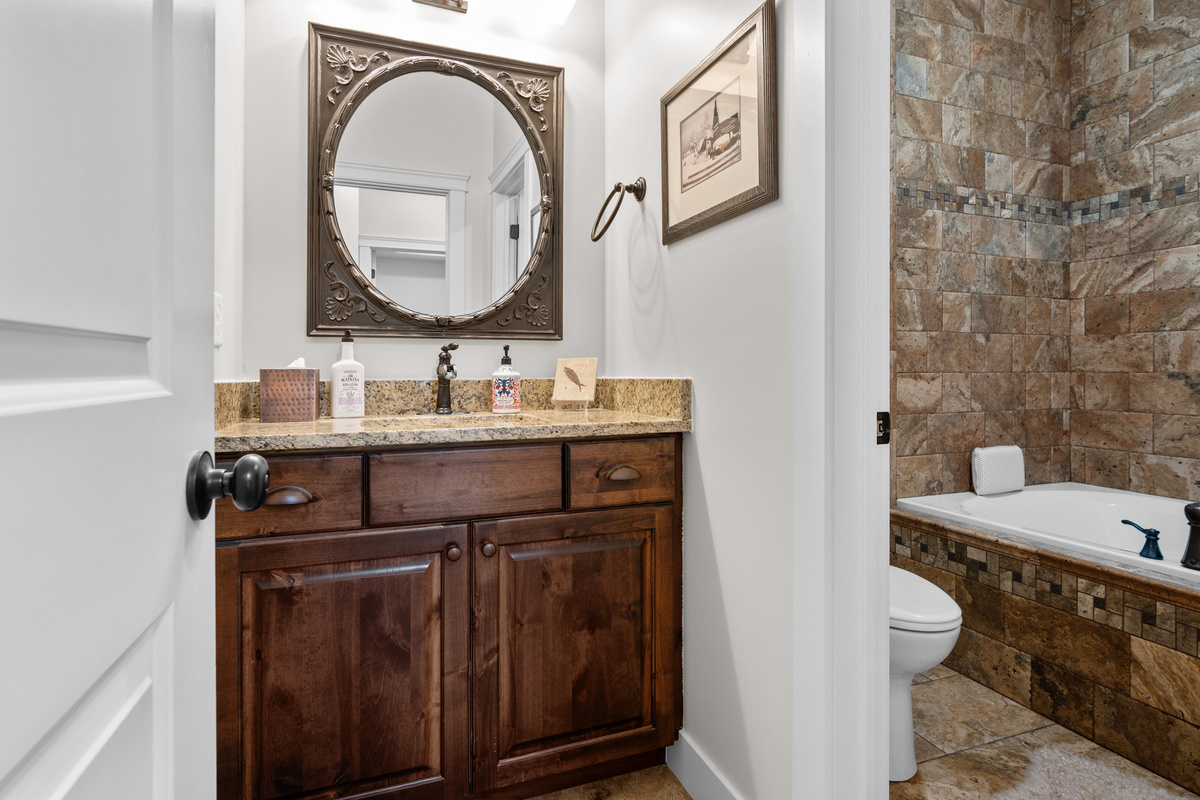 Convenient main-level guest bathroom with granite vanity and beautiful tile finishes located near the office/guest room.