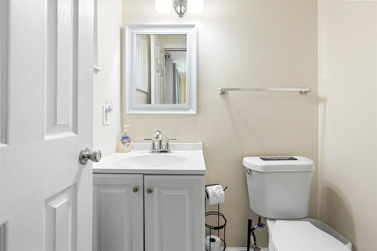 The white vanity features classic paneled cabinet doors and a smooth, solid-surface countertop with an integrated sink.
