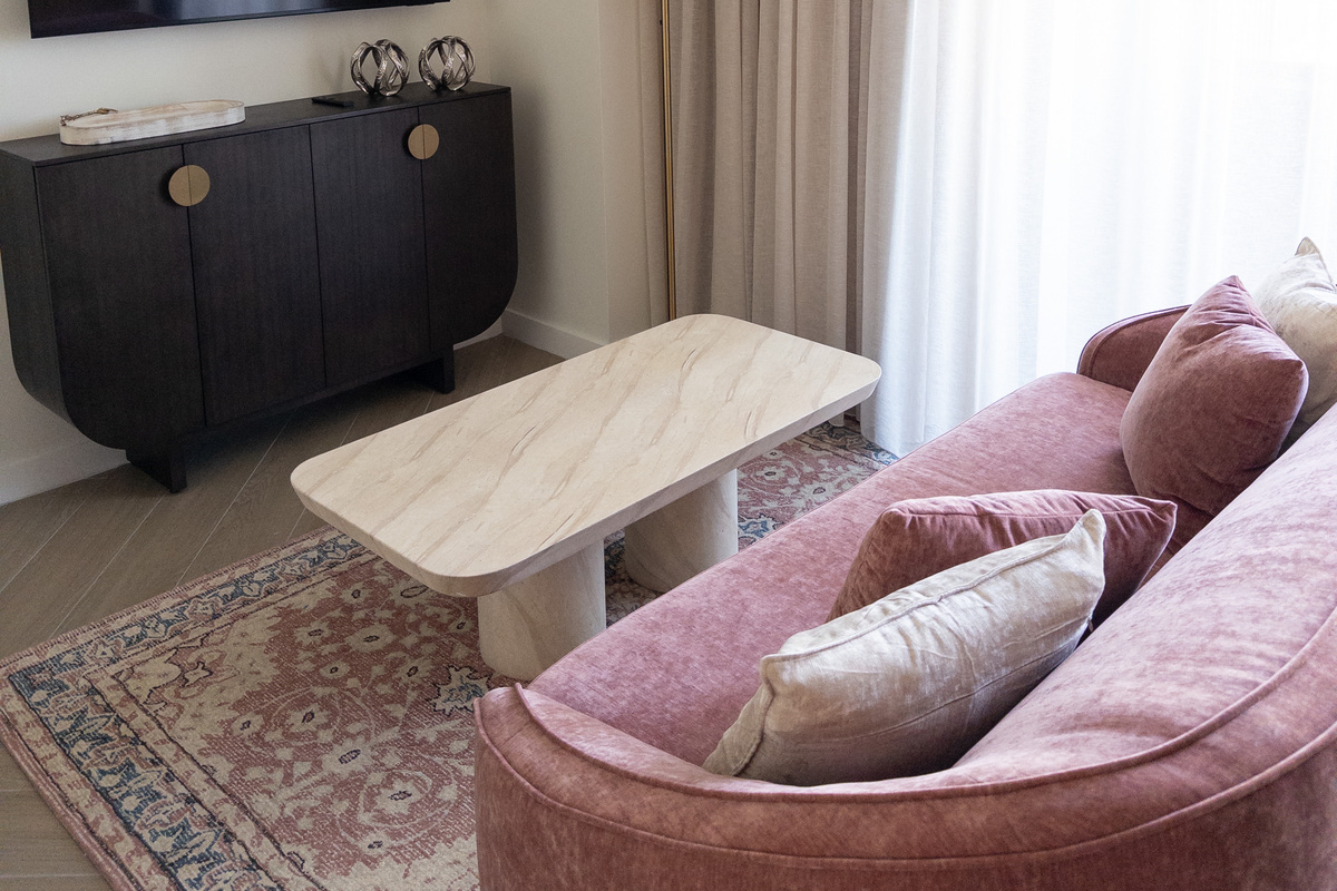 Open-concept living - a sculptural sofa and travertine table over a vintage-style rug.