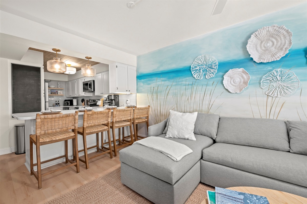 Unwind in the light-filled living space, where coastal hues, plush seating, and a beach-inspired mural set the tone for relaxed mornings and evenings.