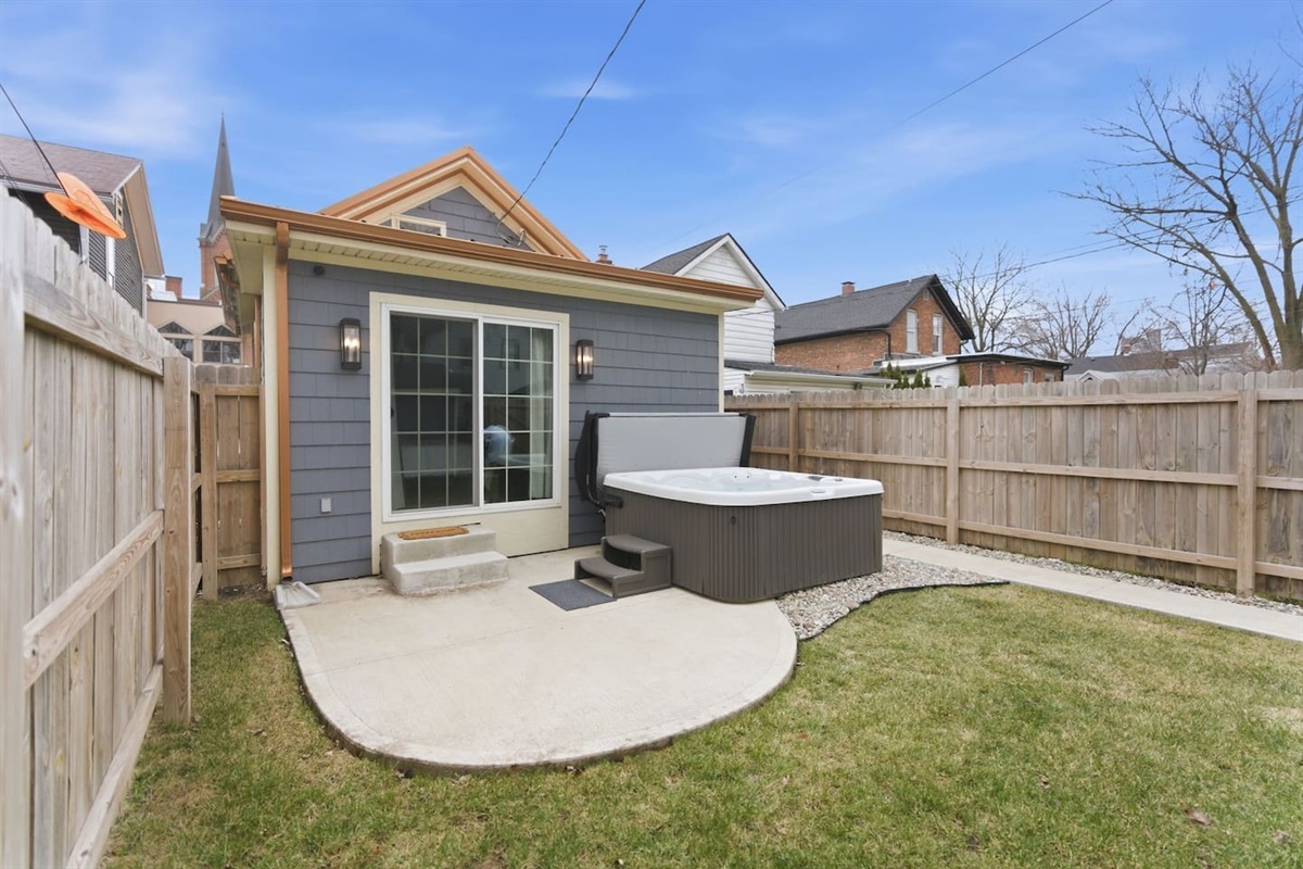 Backyard view featuring a hot tub with easy access from the home