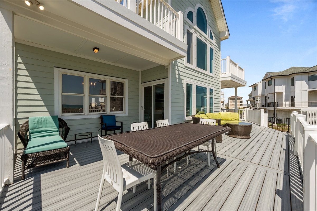 Spacious outdoor deck area with multiple tables and chairs, perfect for a relaxing day.