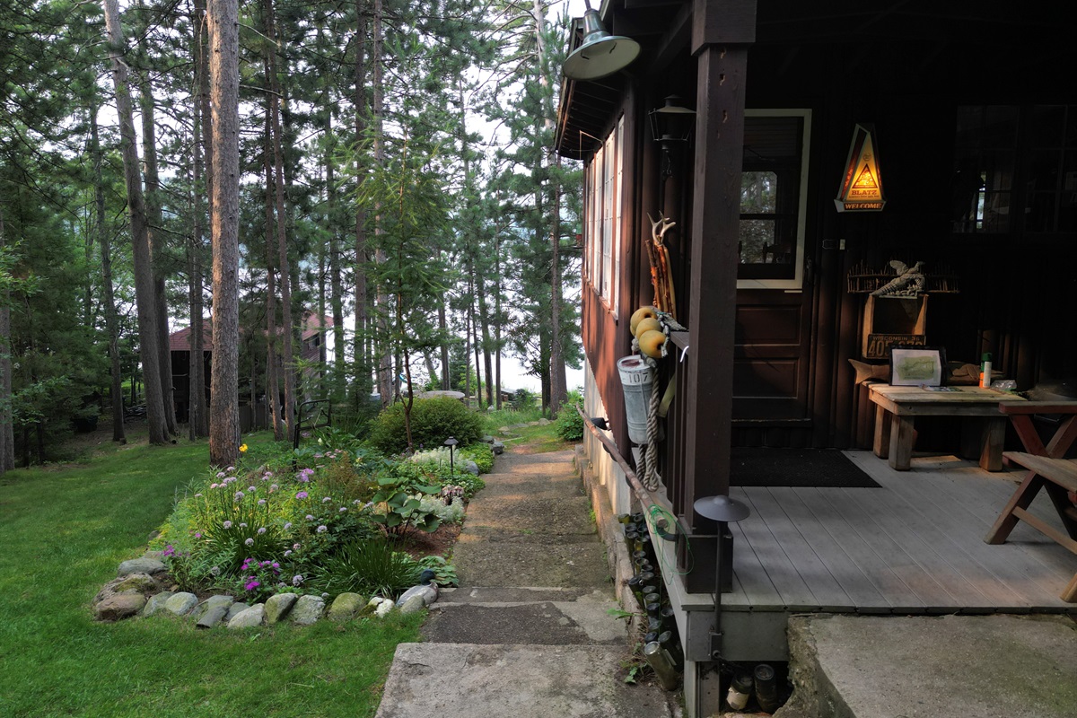 View of entry door to main lodge and grassy lawn down to lake and boathouse