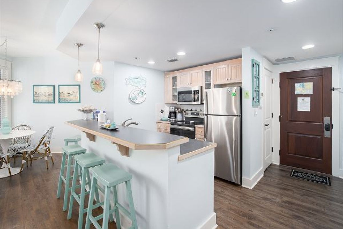 Full kitchen with breakfast bar seating for three, stainless appliances and the entry door