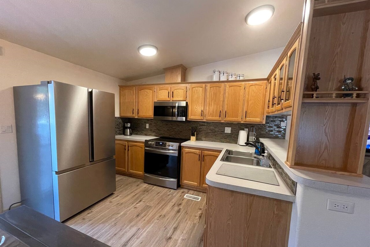 Kitchen with Updated Appliances, Backsplash, Faucet, Cupboard Door Handles, Light, Table, and Flooring