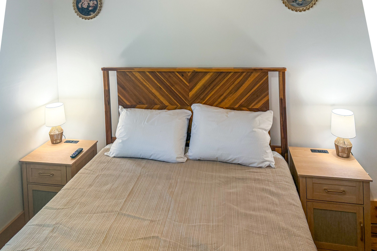 Easily plug in your devices using the built-in USB charging ports situated directly on the wooden nightstands. This straight-on view highlights the plush memory foam queen bed, twin ambient reading lamps, and symmetrical bedroom layout.