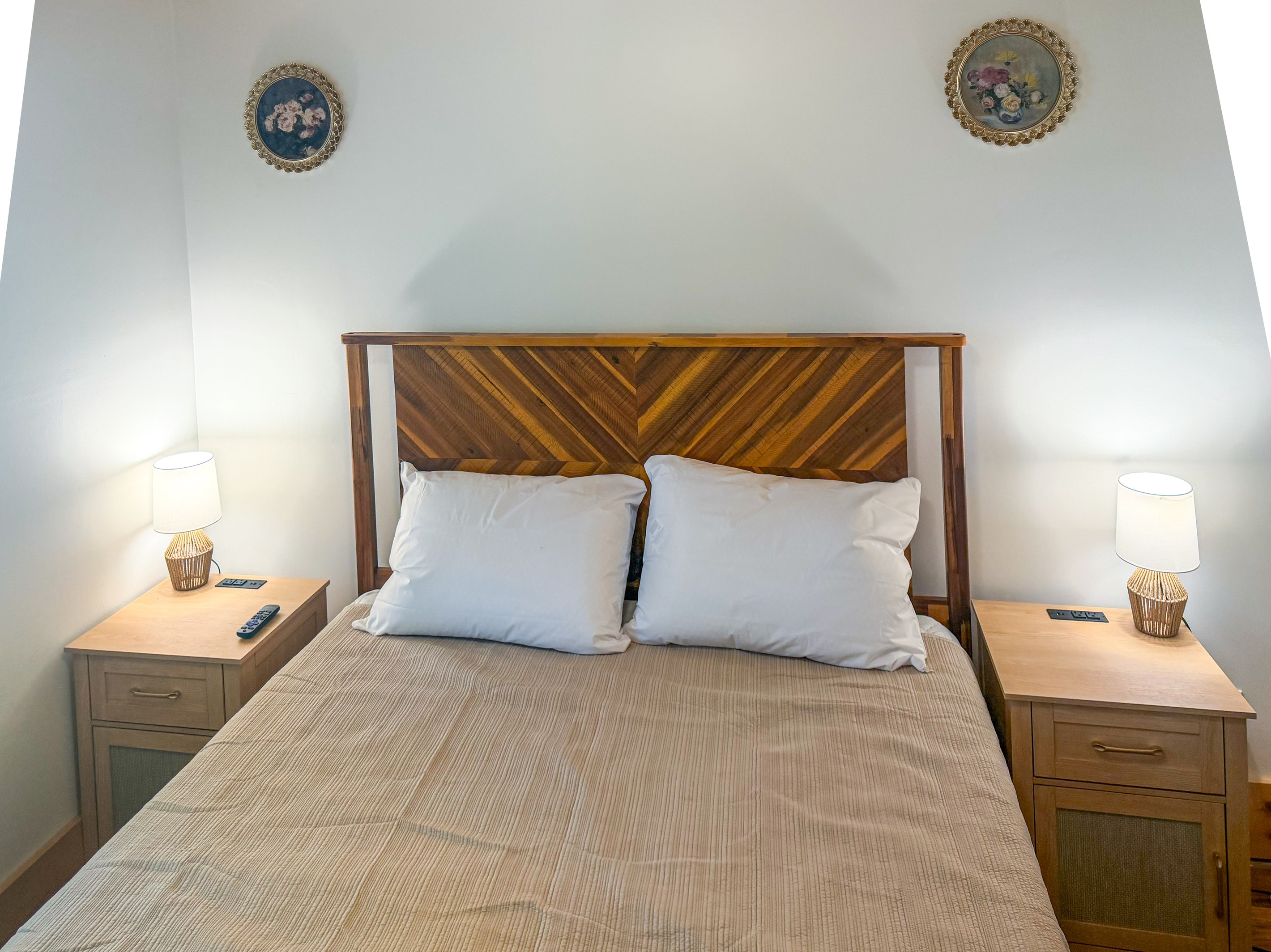 Easily plug in your devices using the built-in USB charging ports situated directly on the wooden nightstands. This straight-on view highlights the plush memory foam queen bed, twin ambient reading lamps, and symmetrical bedroom layout.