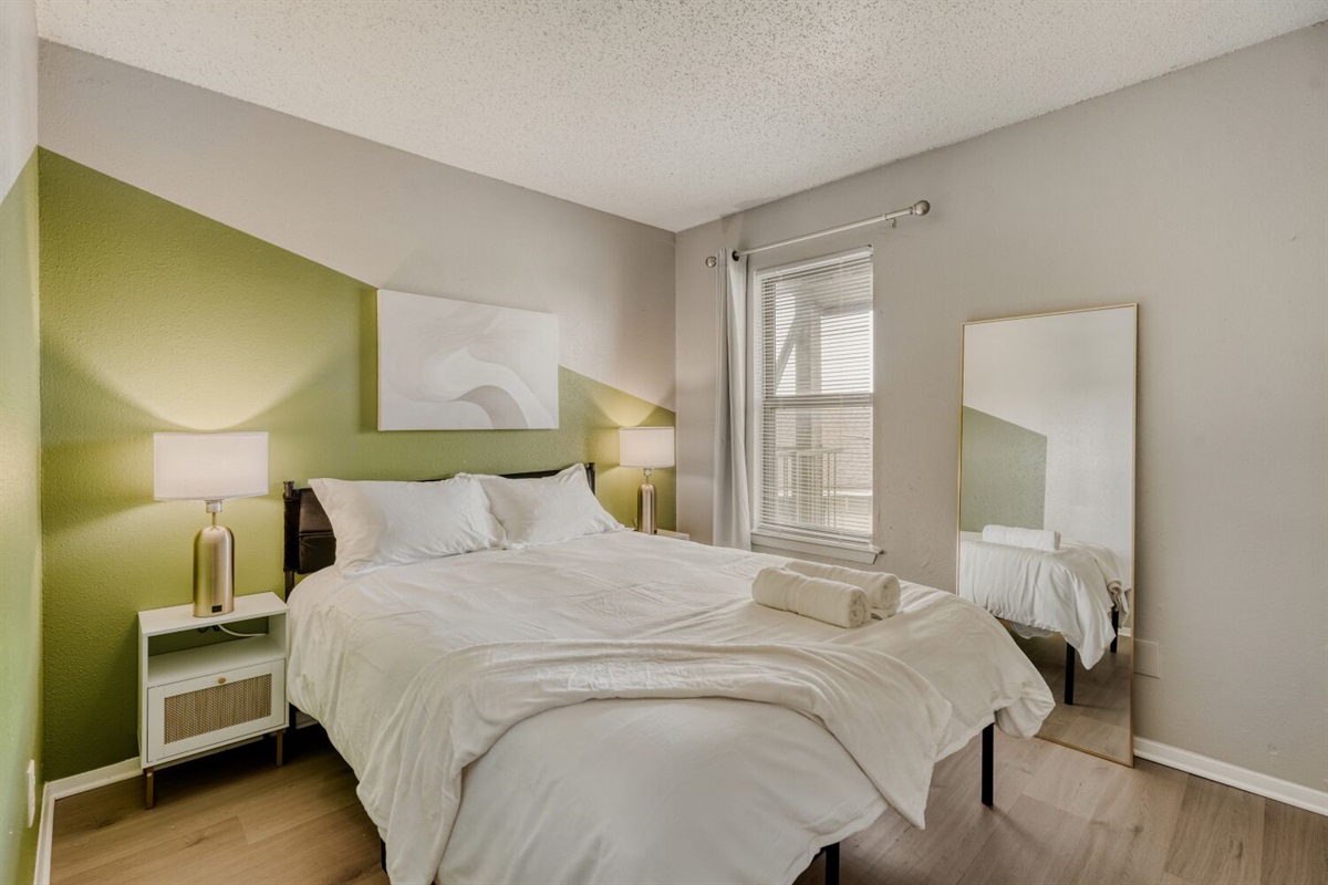 Bright and cozy bedroom with a modern green accent wall and soft natural light.