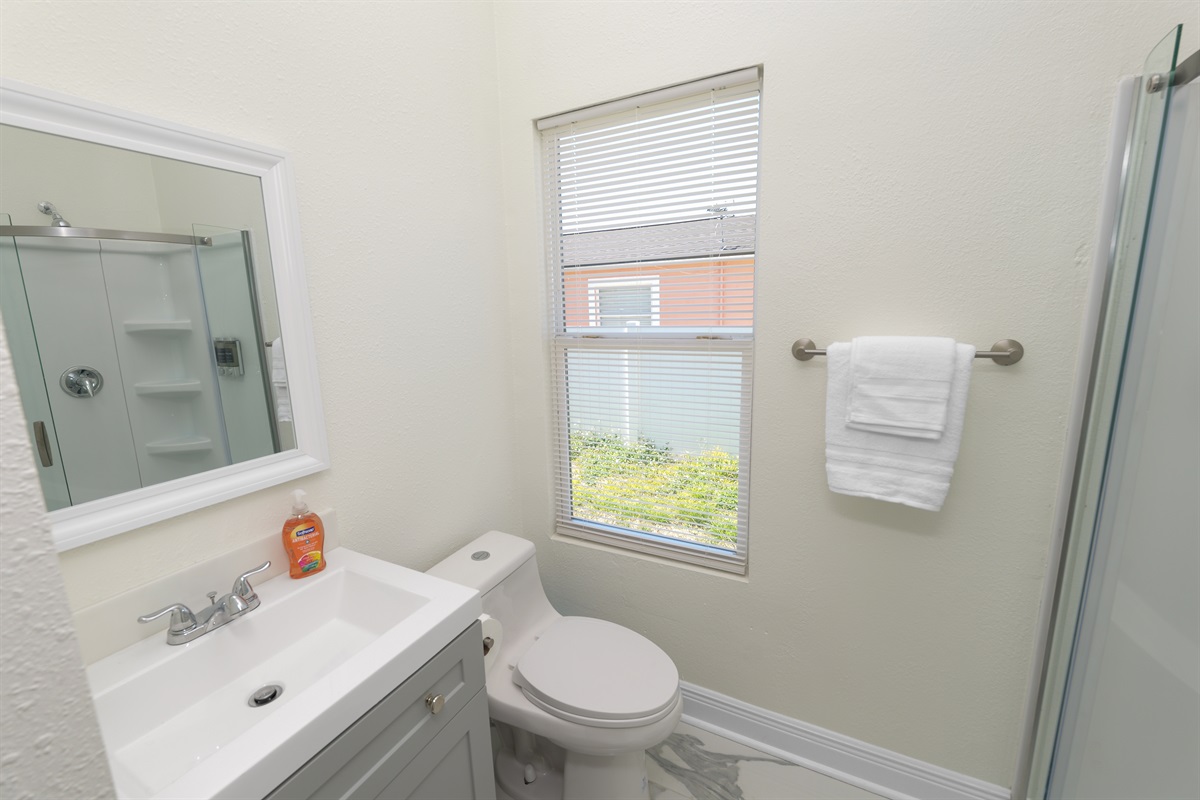 Bright and thoughtfully designed, this full bathroom offers a space-saving walk-in shower with smooth sliding doors and built-in shelving for a clutter-free stay.