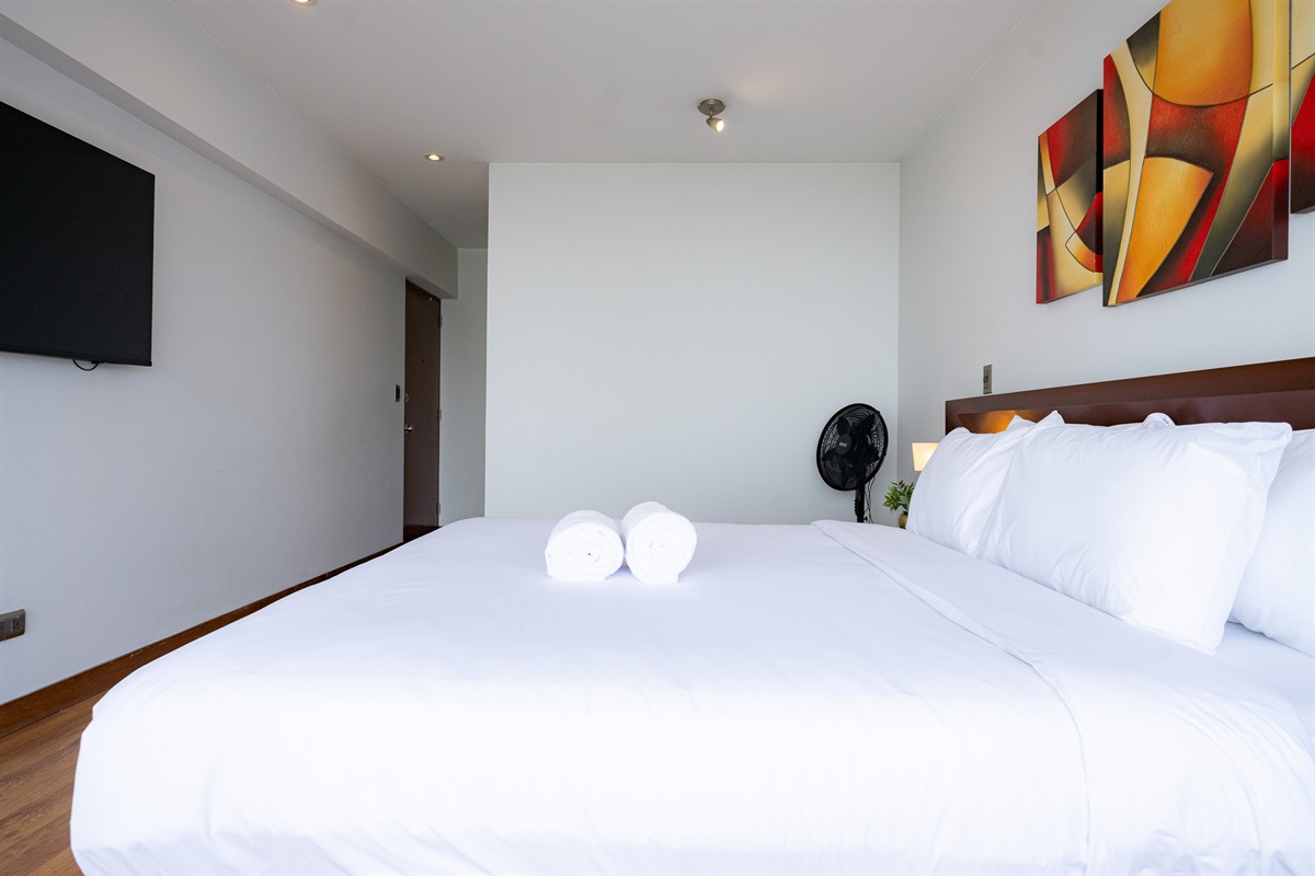 Master bedroom with queen-size bed, 55” Smart TV, and private en-suite bathroom  /  Dormitorio principal con cama queen, Smart TV de 55” y baño privado