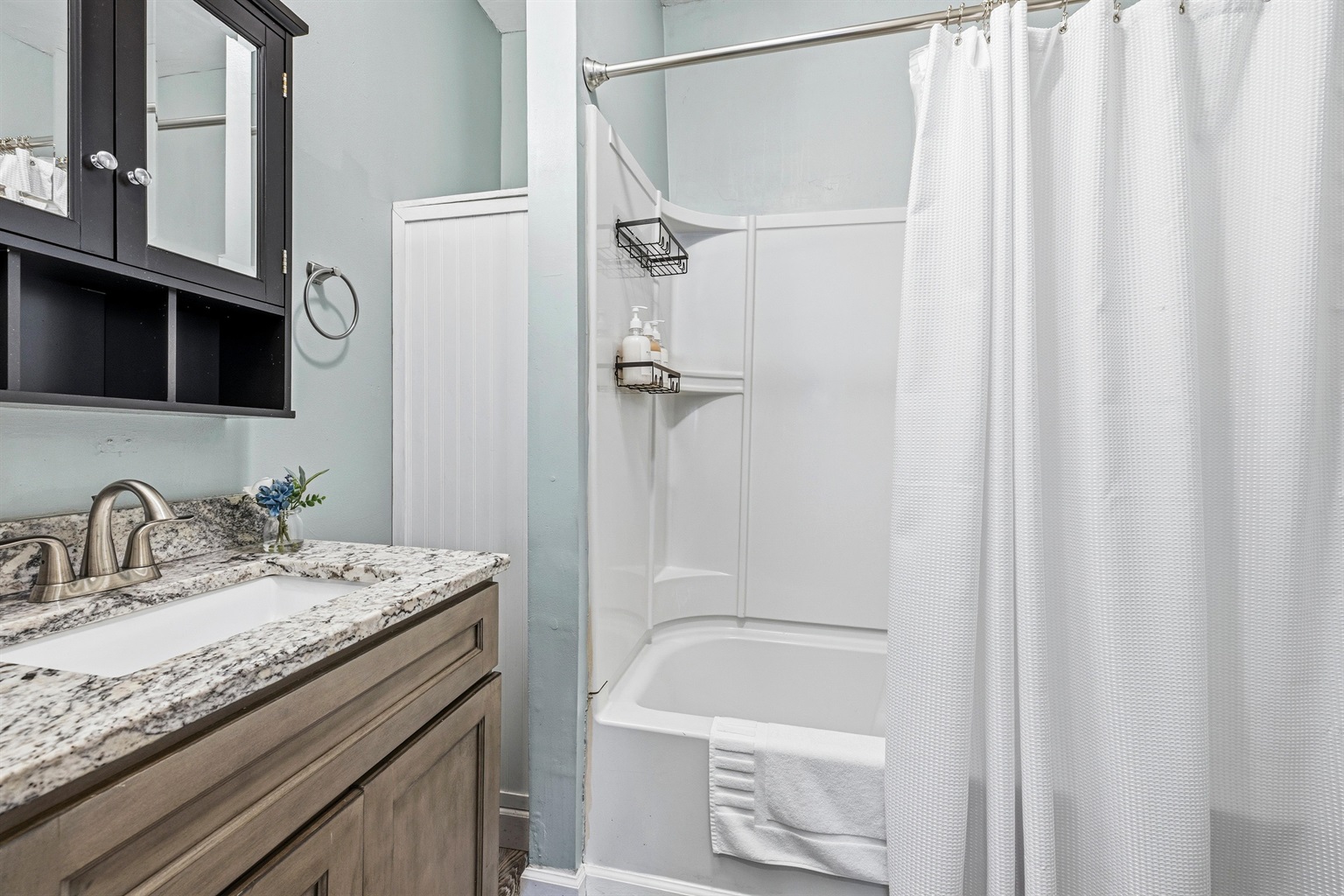 Bathroom with granite counters on the vanity and a shower/tub combination.