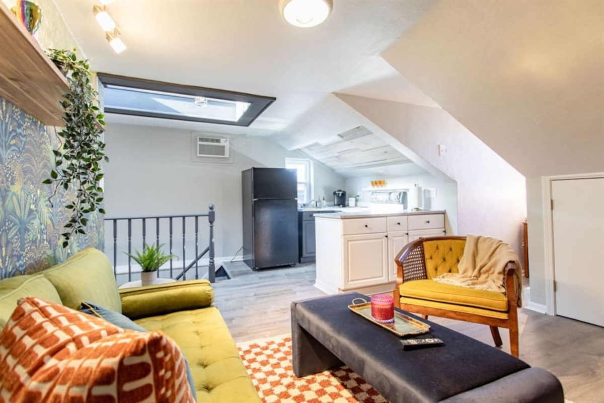 Experience the seamless blend of comfort and functionality in this open-concept living and kitchen space. The skylight floods the area with natural light, enhancing the modern design. The fully equipped kitchen, with its sleek appliances and ample co