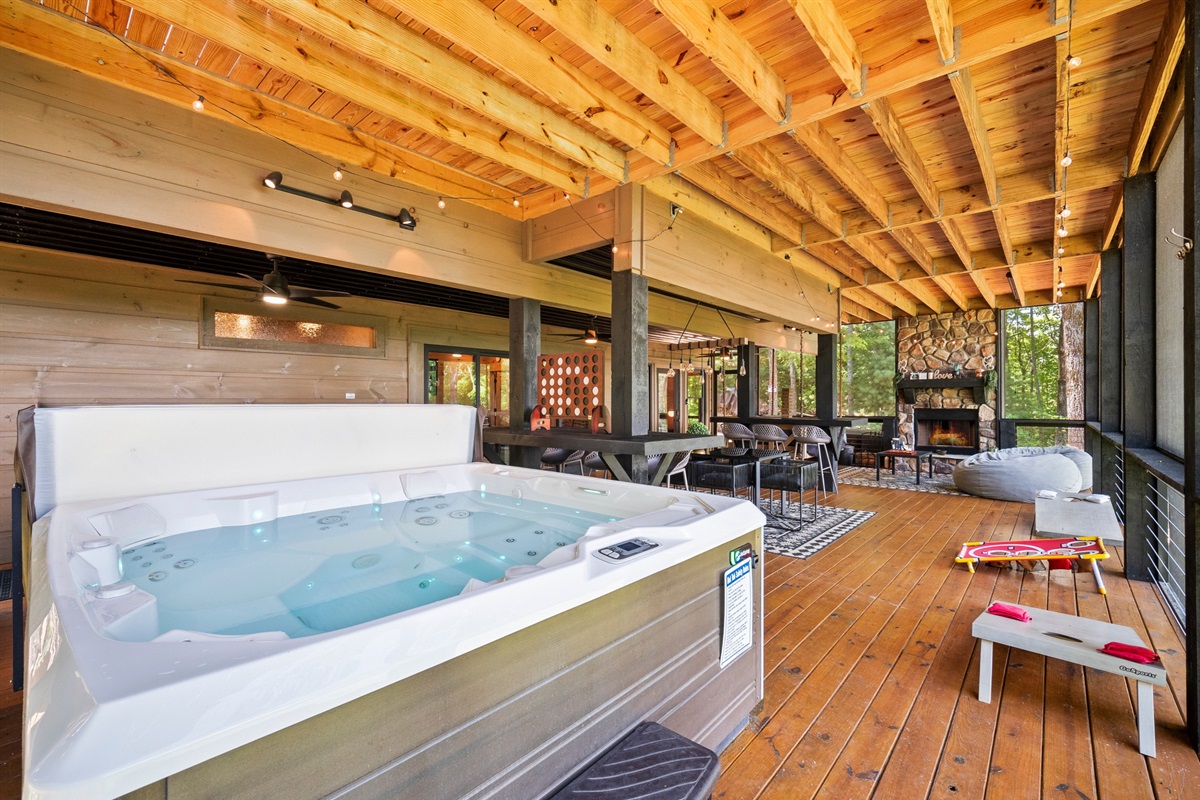 Soak, dine and unwind. This expansive covered deck features a private hot tub, cozy outdoor fireplace, dining space, and games, making it the ultimate mountain hangout spot.