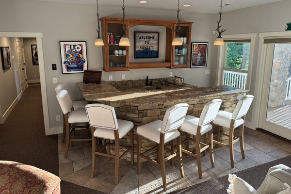 Spacious lower-level living area with a large bar, comfortable seating, and waterfront views