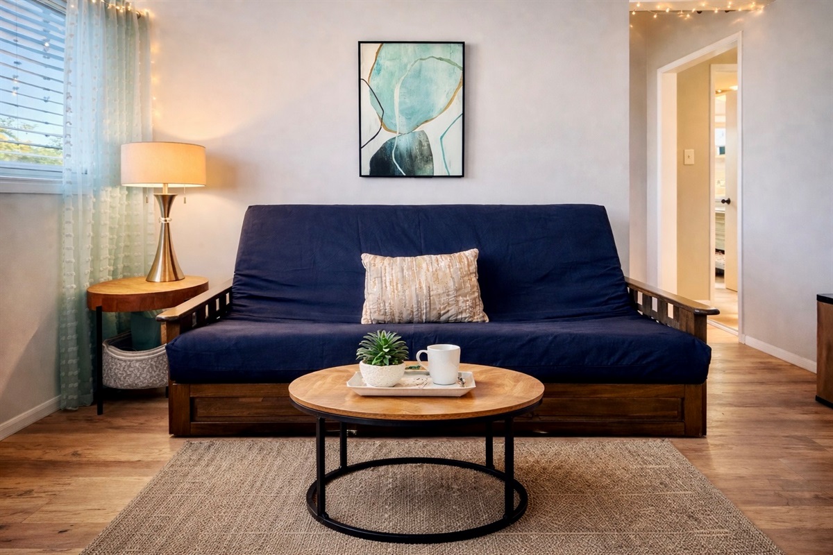 Cozy living room with futon (linens in the bin) smart TV and vaulted ceiling.