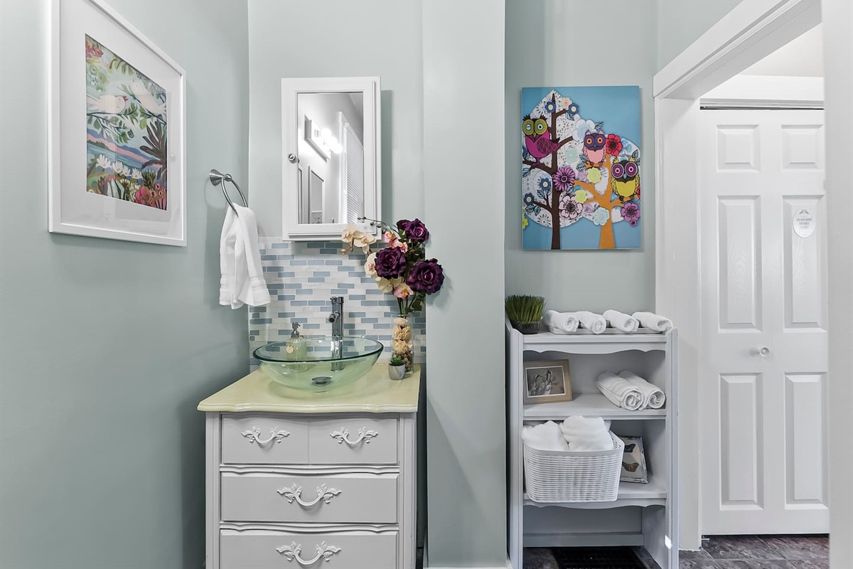 Charming vanity space with a glass vessel sink, framed mirror, and elegant accents, ideal for getting ready with ease
