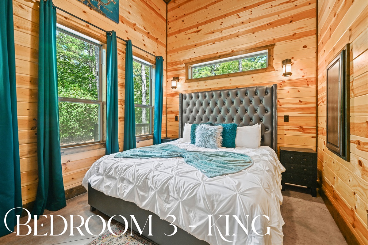 Bedroom 3 offers a plush king bed, striking headboard, and large windows that bring in the calming outdoor scenery.