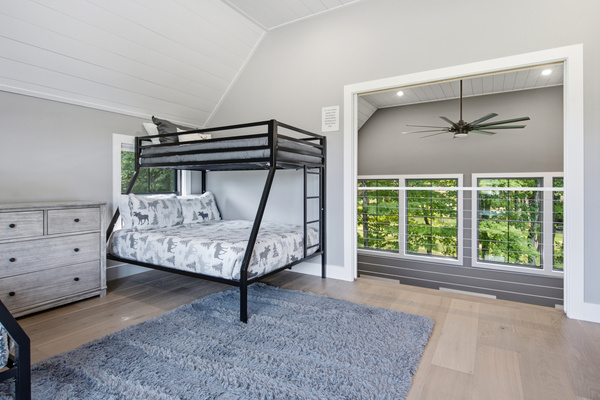 Bright windows and comfortable bunk beds create a welcoming retreat surrounded by natural scenery.