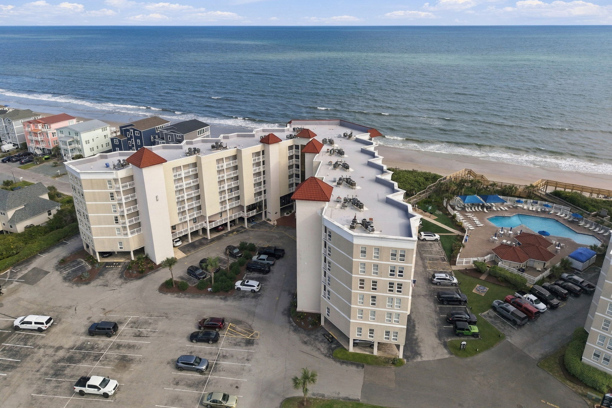 Aerial shot showcasing the resort complex, shoreline, and vibrant blue ocean waters.