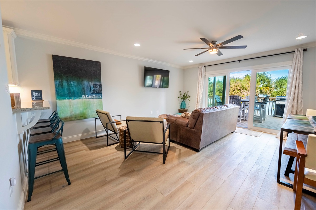 Cozy coastal living room with beach decor and sunny deck access for relaxation.