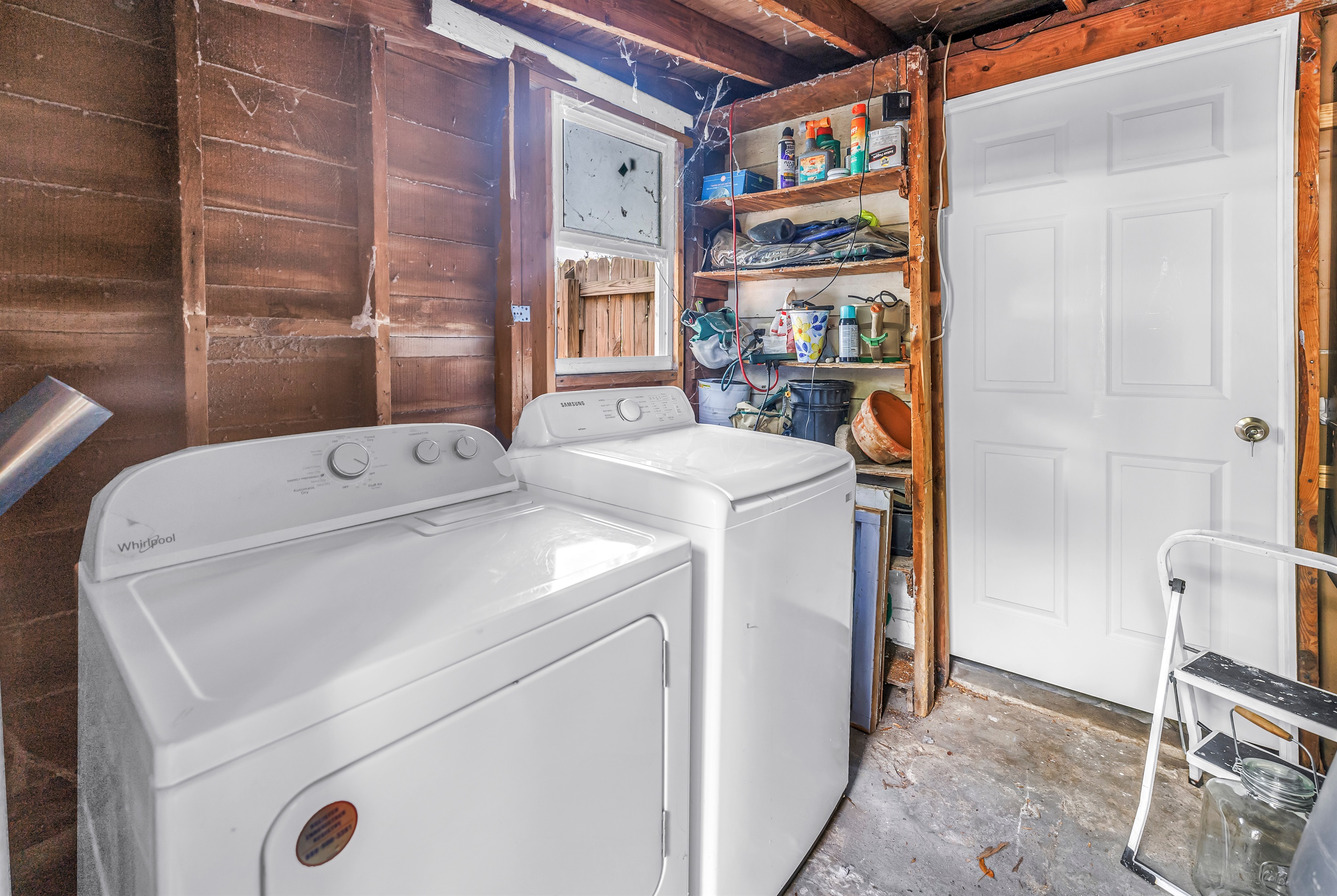 Laundry area with washer, dryer, utility shelving, and extra storage space for everyday convenience.