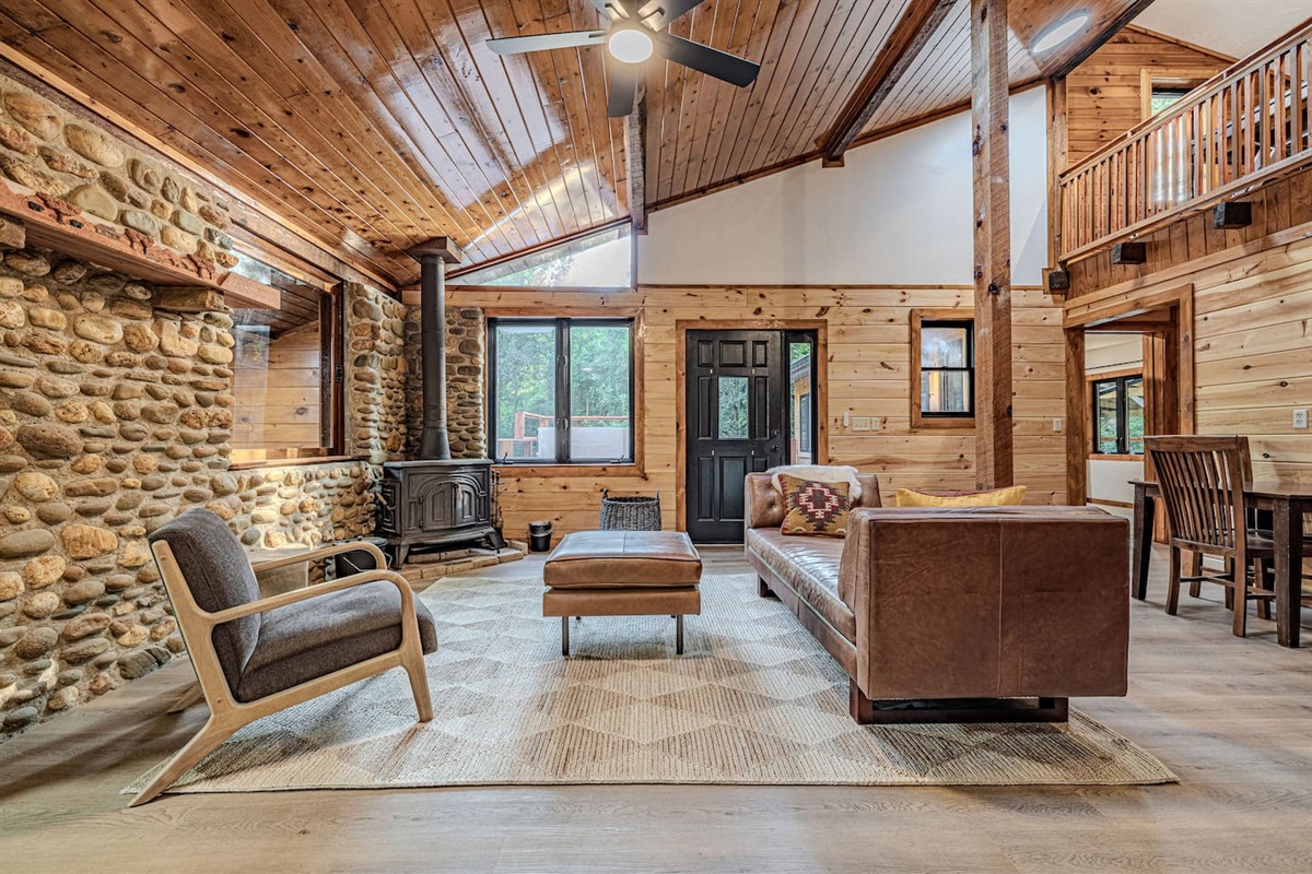 Soaring cathedral ceilings and stunning original stone walls anchor this additional living area, where a decorative wood-burning stove and plush seating evoke timeless Smoky Mountain elegance.