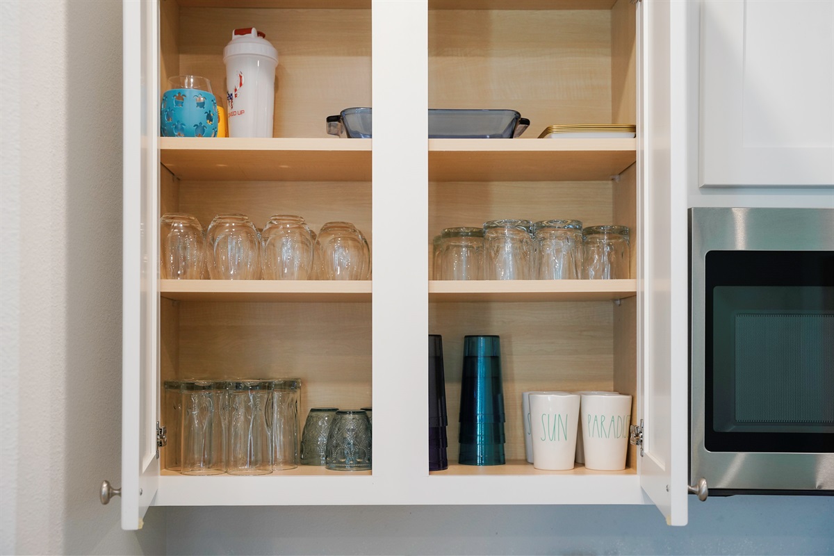 Fully stocked kitchen with utensils, plates, cups, and glasses
