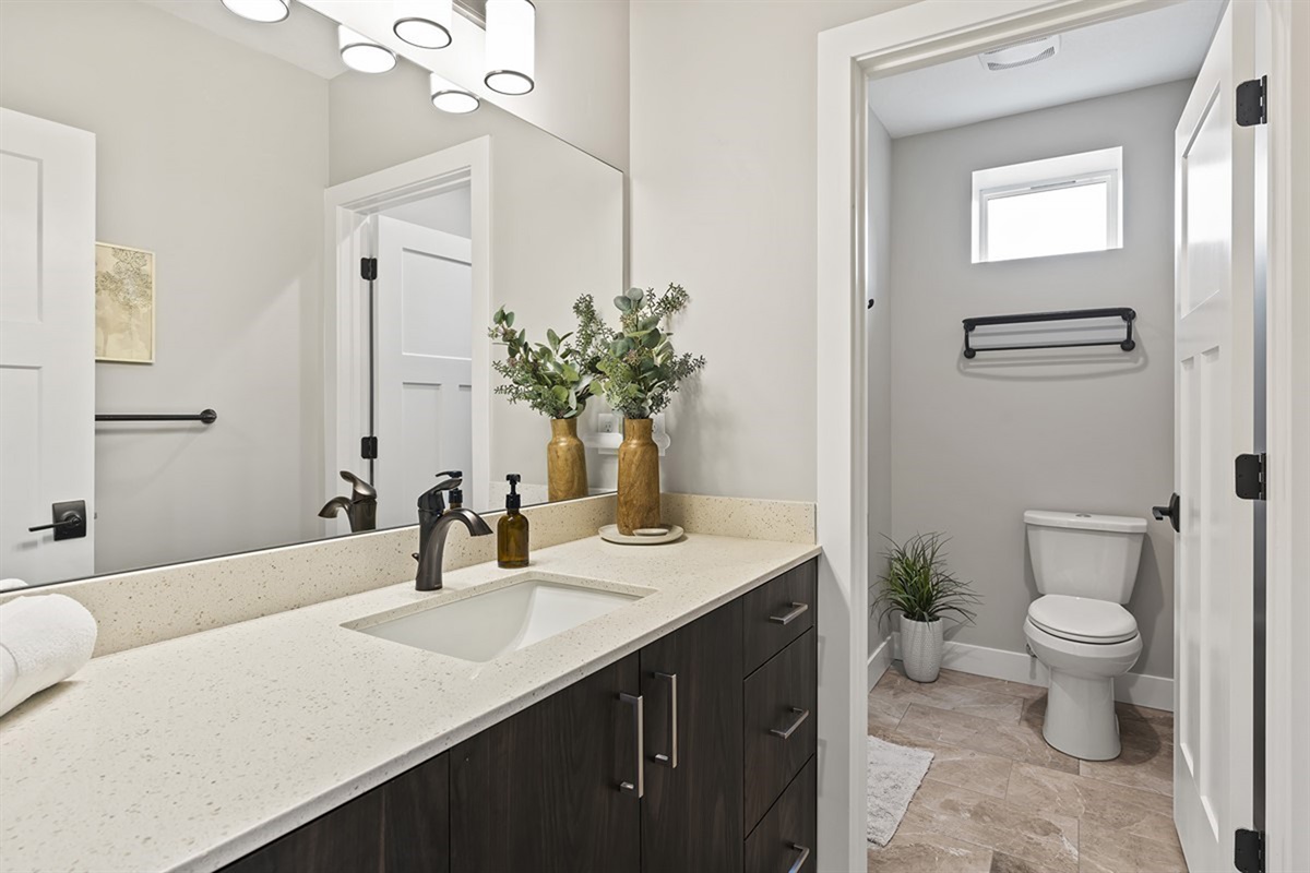 Bright bathroom with modern vanity and adjacent toilet area