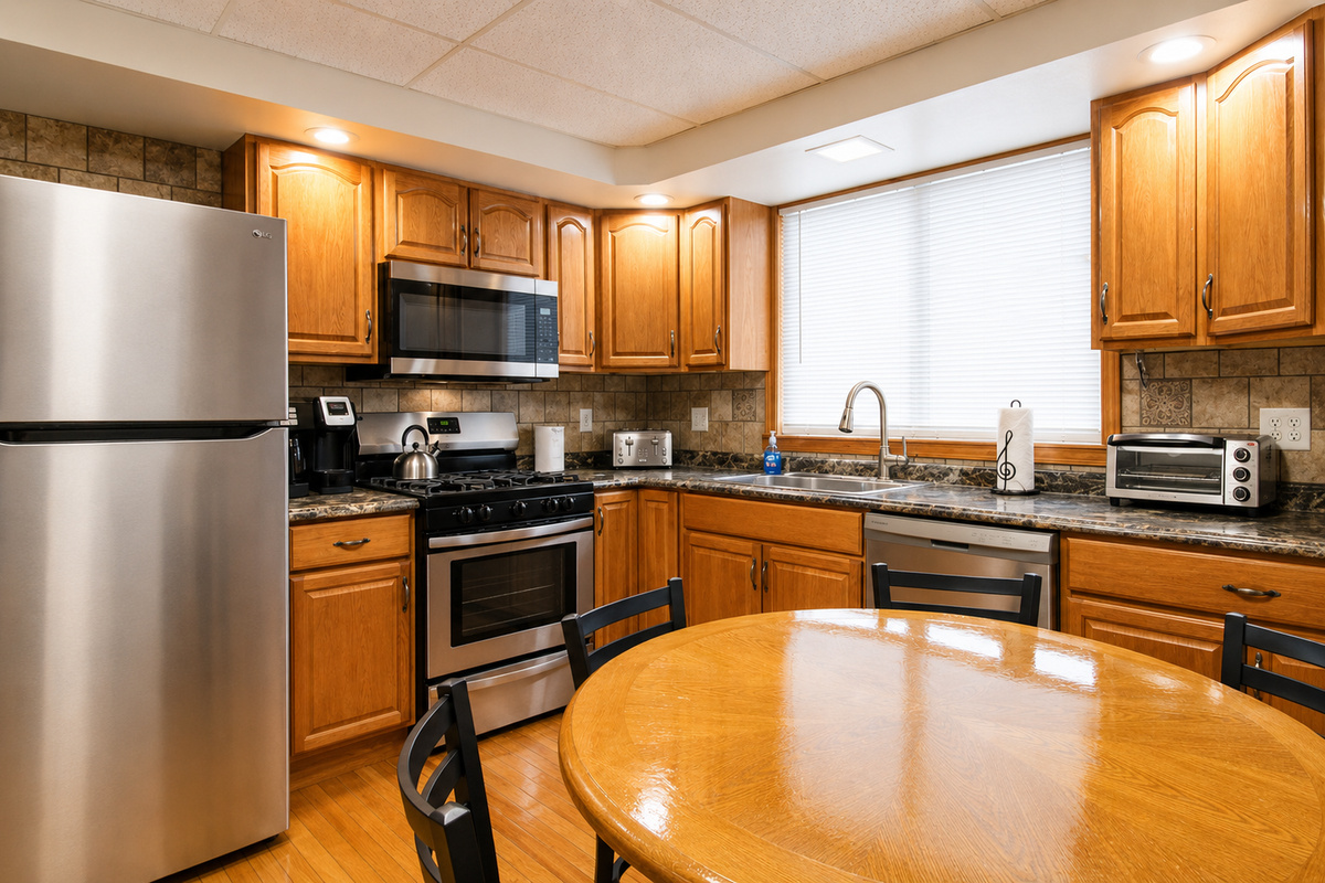 Fully equipped kitchen with hardwood floors and tiled backsplash.  Features a gas range, microwave, dishwasher, and full size refrigerator with automatic ice maker.