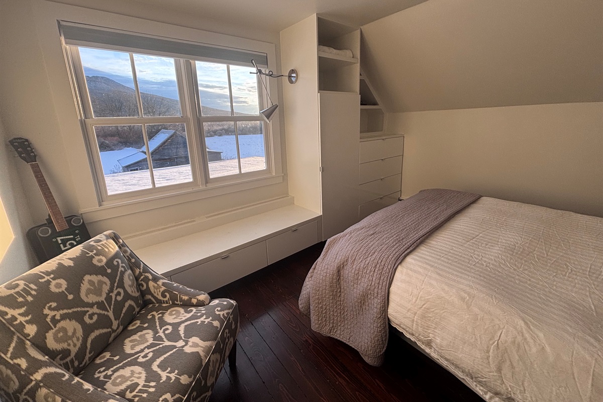 Charming single bedroom with built-in storage and tranquil outdoor views.