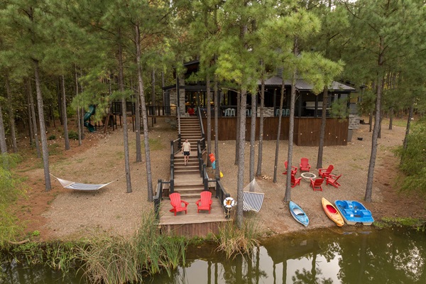A closer look at the cabin’s private lake access, complete with kayaks, a paddle boat, and red Adirondack chairs by the firepit. A dream location for fishing, paddling, or simply unwinding by the water.