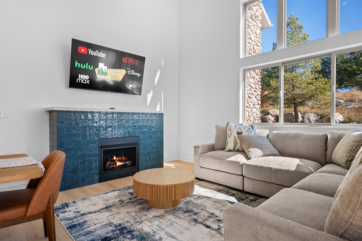 The living room boasts abundant natural light, a welcoming fireplace, and a large screen smart TV.