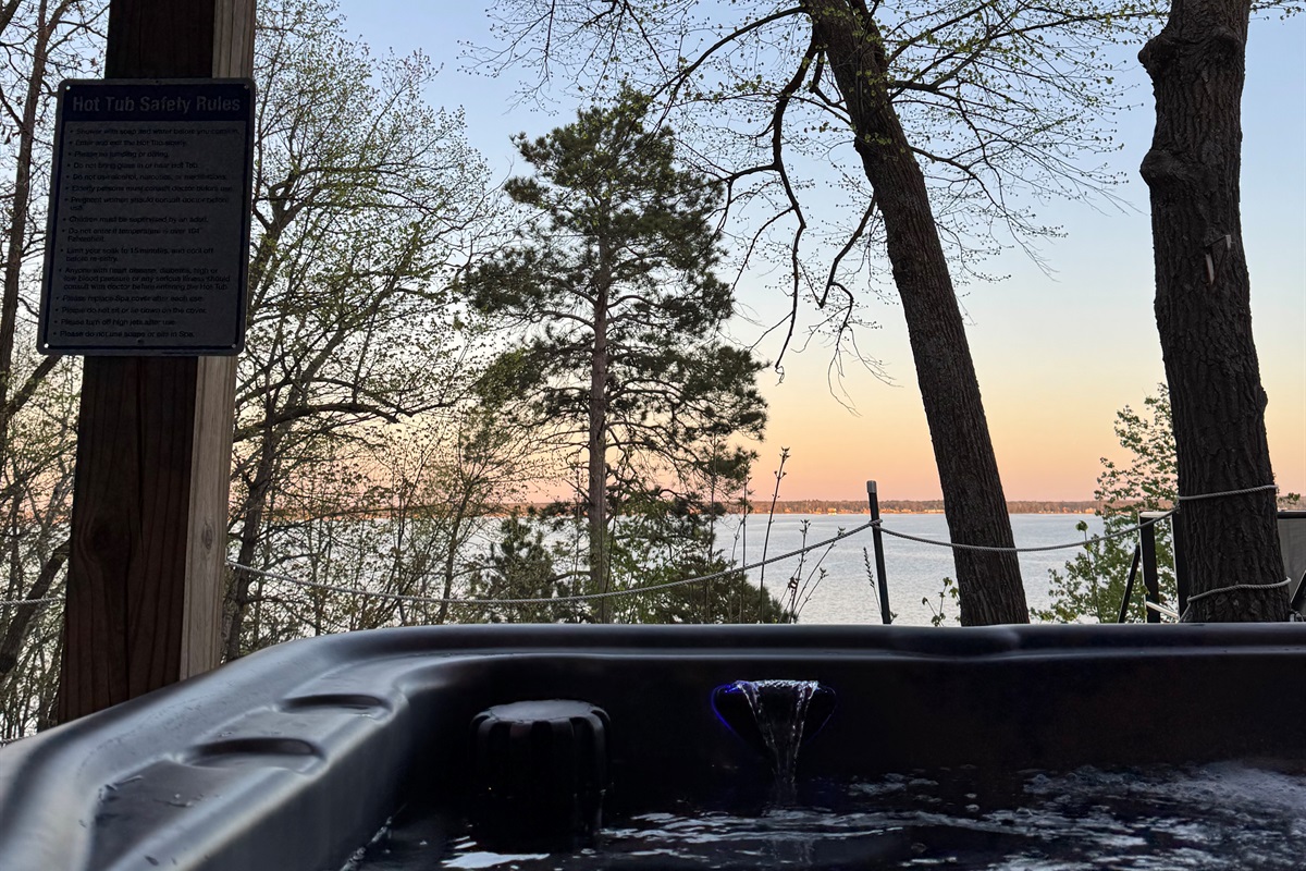 POV: You're relaxing in our hot tub, watching the lake beyond a majestic Norway Pine.