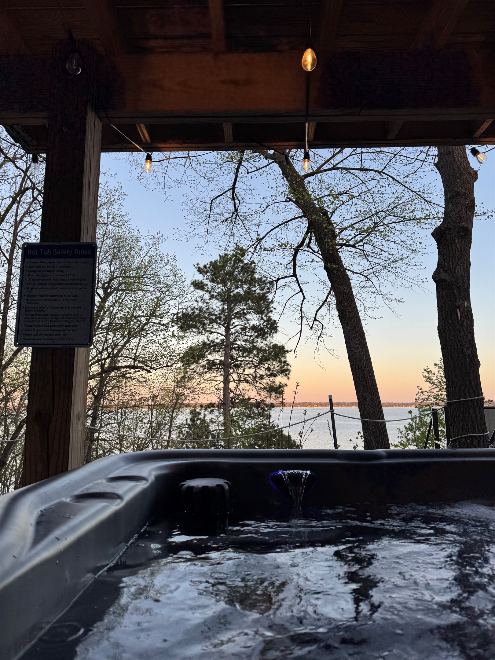 POV: You're relaxing in our hot tub, watching the lake beyond a majestic Norway Pine.