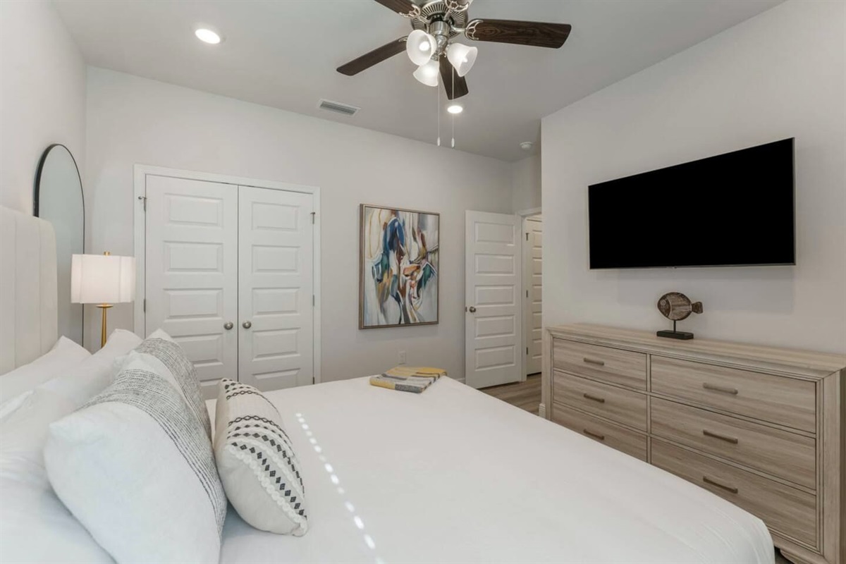 Comfortable and airy bedroom with natural light, a ceiling fan, and thoughtful bedside details.