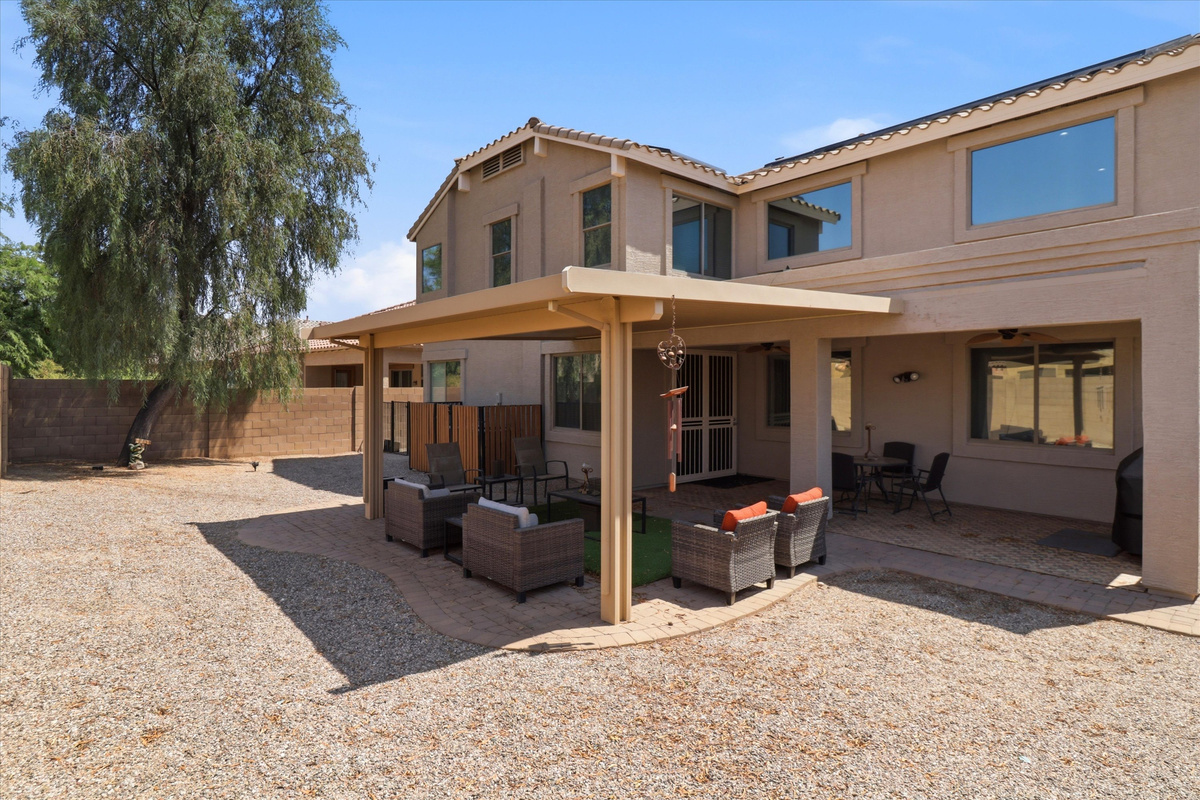 Backyard with a covered patio, outdoor seating, and a large open yard for fresh air.
