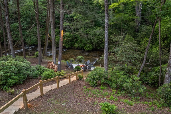 Custom landscape uplighting creates a magical ambiance, guiding your steps with a warm glow as you wander to and from the firepit and the tranquil creek.