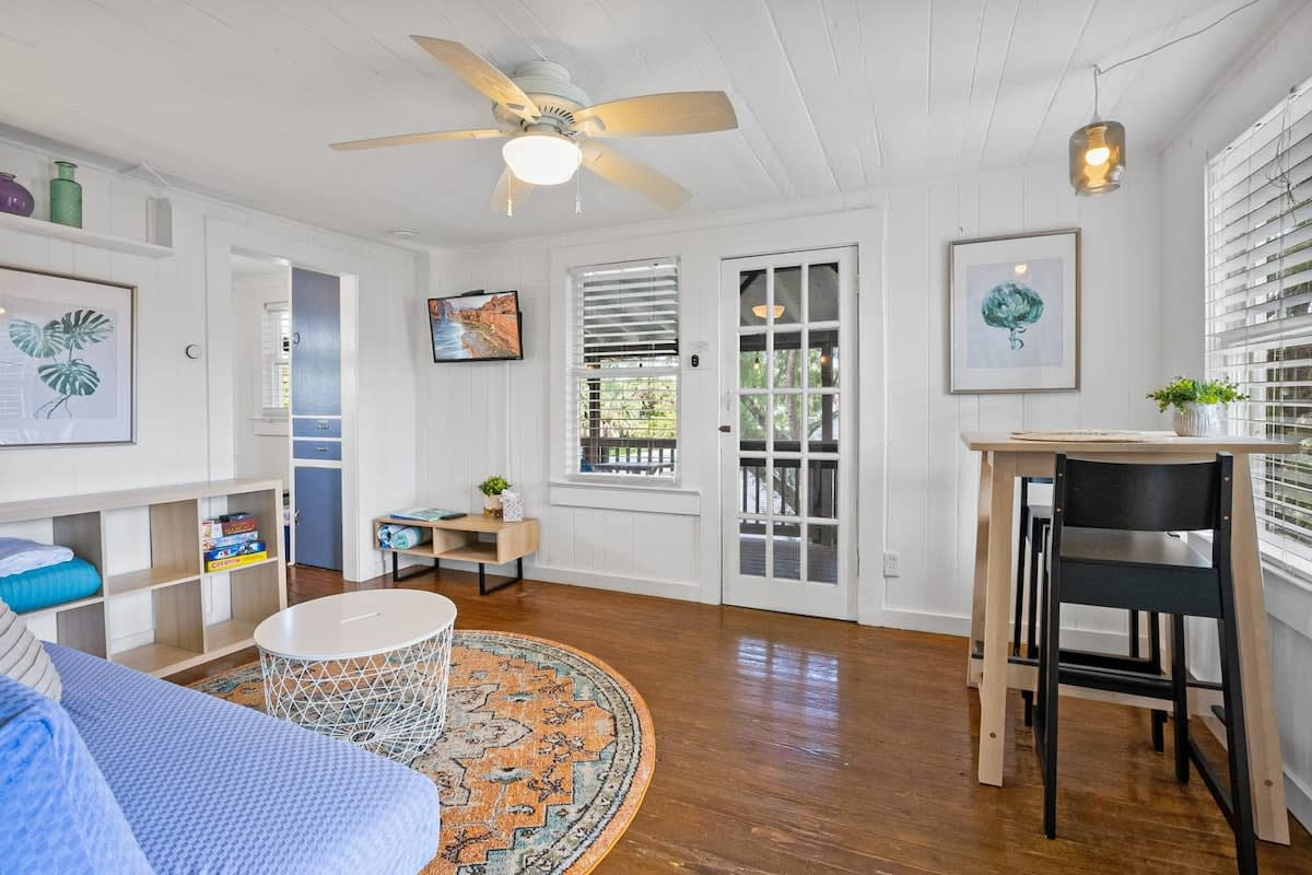Light pours through this room from morning until evening. Ceiling fans turn overhead, the French doors stand open to the balcony, and the whole apartment feels like somewhere you can finally put your shoulders down and exhale.